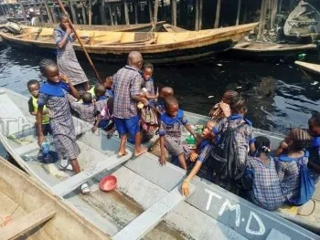 Two boys sitting on a wooden boat on a river in Nigeria